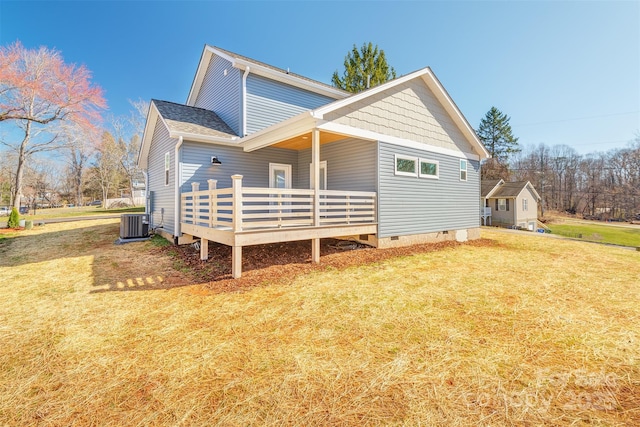 rear view of property with a shingled roof, a wooden deck, a yard, and crawl space