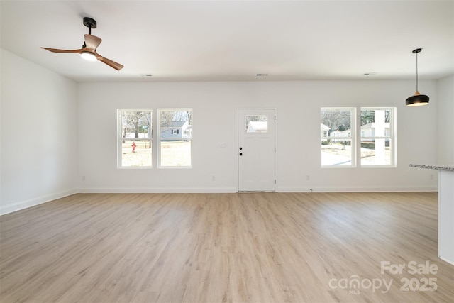 unfurnished living room featuring light wood-type flooring, baseboards, and a ceiling fan