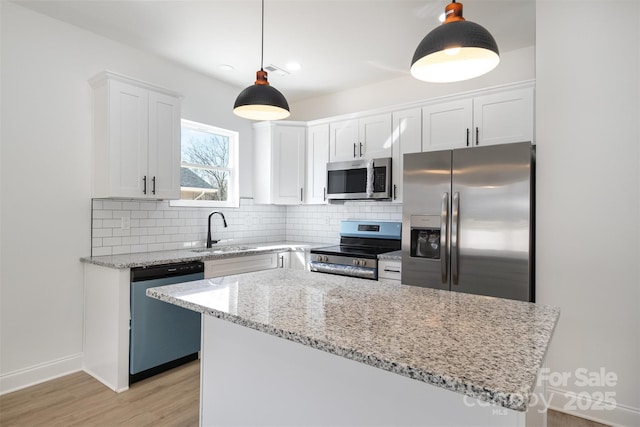 kitchen with stainless steel appliances, a sink, white cabinets, backsplash, and light stone countertops