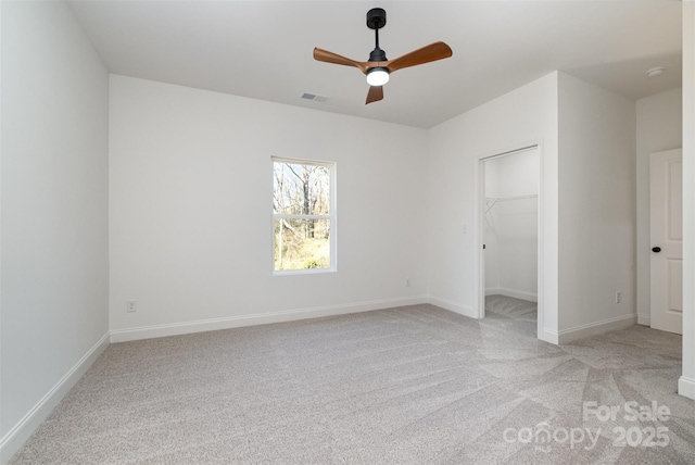 unfurnished bedroom featuring baseboards, a spacious closet, visible vents, and light colored carpet