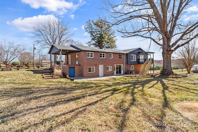 rear view of property featuring brick siding, a yard, and stairway