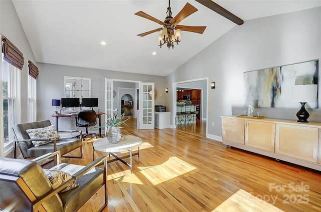 living area featuring baseboards, light wood-style flooring, ceiling fan, high vaulted ceiling, and beam ceiling