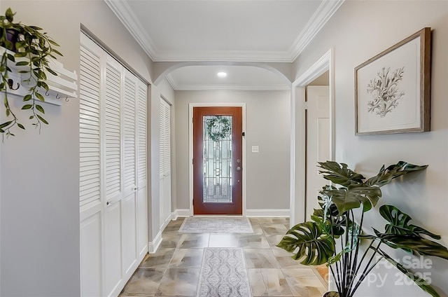 foyer entrance with baseboards, arched walkways, and ornamental molding