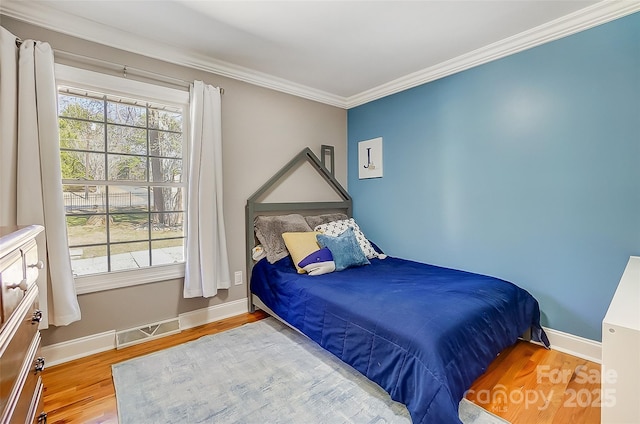 bedroom featuring crown molding, multiple windows, visible vents, and wood finished floors