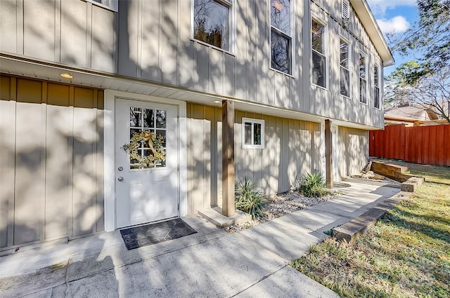 doorway to property featuring board and batten siding and fence