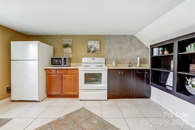 kitchen with white appliances, vaulted ceiling, light tile patterned floors, and light countertops