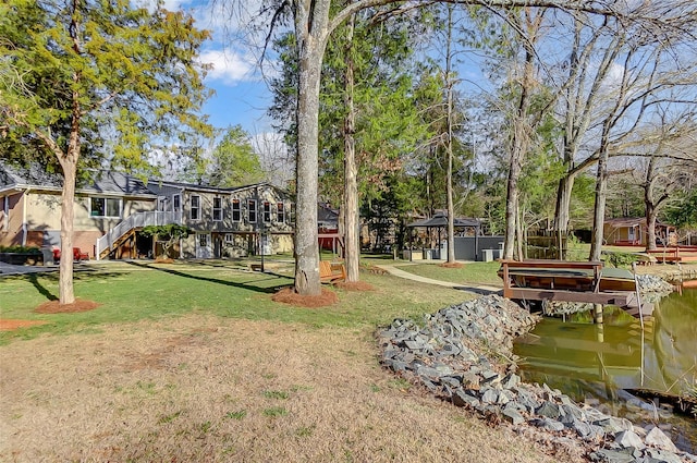 view of property's community featuring stairs, a deck with water view, and a yard