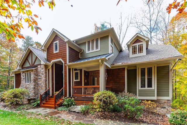 view of front of house with metal roof, stone siding, roof with shingles, and a porch