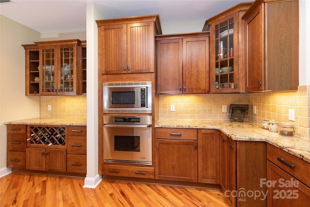 39 Hawks Pointe Ln, Weaverville, NC 28787 - kitchen with stainless steel appliances, light wood finished floors, tasteful backsplash, glass insert cabinets, and light stone counters