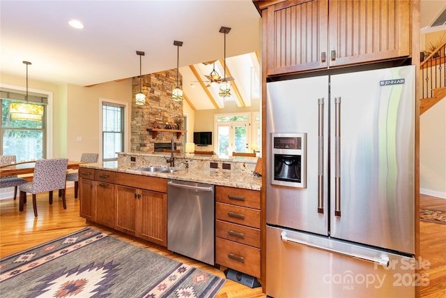39 Hawks Pointe Ln, Weaverville, NC 28787 - kitchen with stainless steel appliances, brown cabinetry, light wood-style floors, a sink, and a stone fireplace