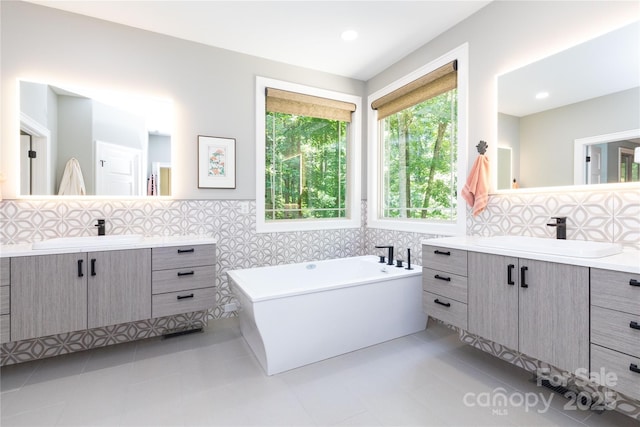 39 Hawks Pointe Ln, Weaverville, NC 28787 - full bathroom featuring two vanities, a soaking tub, tile walls, tile patterned floors, and tasteful backsplash