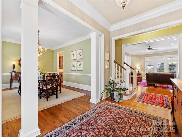 entrance foyer featuring crown molding, decorative columns, stairway, and wood finished floors