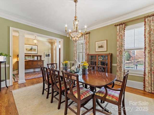 dining room featuring ornate columns, ornamental molding, and wood finished floors