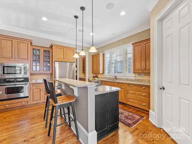 kitchen featuring glass insert cabinets, appliances with stainless steel finishes, crown molding, light wood-style floors, and a sink