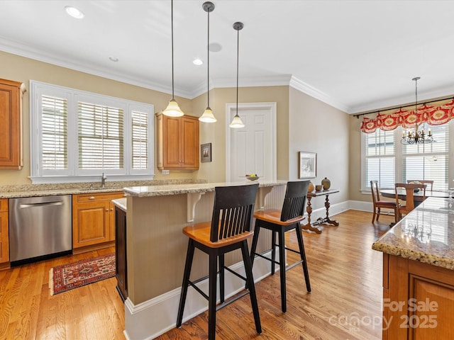 kitchen with a center island, a breakfast bar, light wood-style floors, ornamental molding, and dishwasher