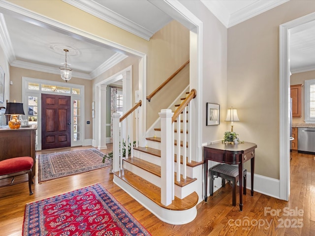 foyer entrance featuring plenty of natural light, wood finished floors, and crown molding