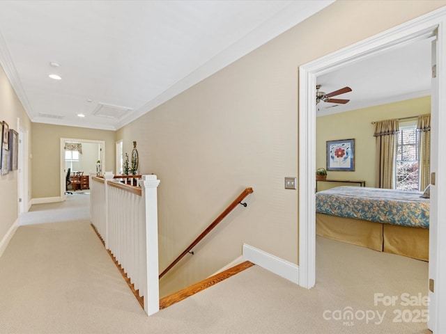 hallway featuring attic access, light colored carpet, crown molding, and an upstairs landing