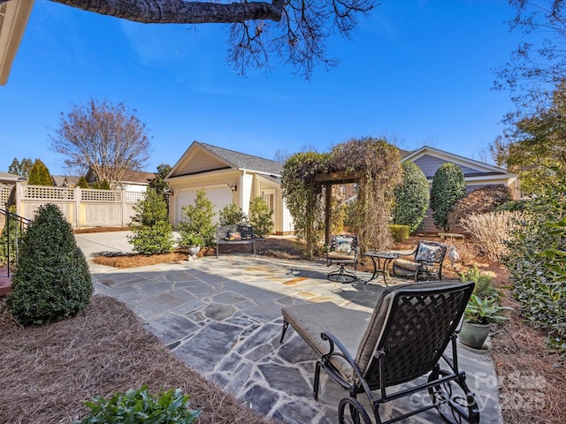 view of patio featuring an attached garage and fence