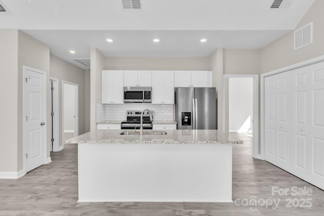 kitchen with appliances with stainless steel finishes, a kitchen island with sink, visible vents, and a sink