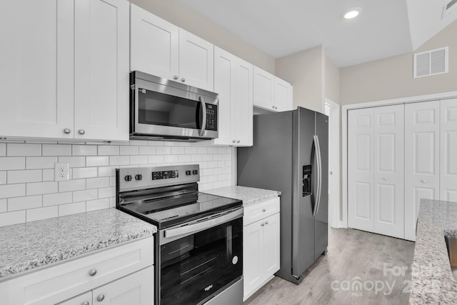 kitchen with visible vents, white cabinets, appliances with stainless steel finishes, light wood-type flooring, and decorative backsplash