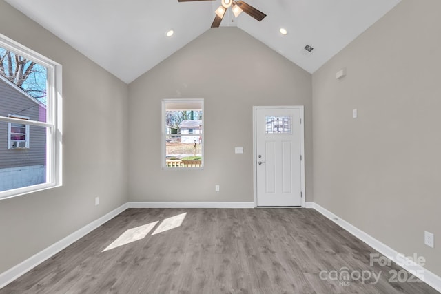 foyer with baseboards, visible vents, a ceiling fan, wood finished floors, and high vaulted ceiling