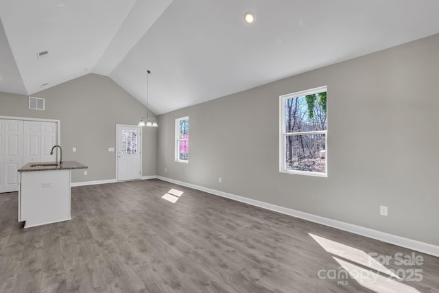 unfurnished living room featuring a chandelier, visible vents, dark wood finished floors, and baseboards