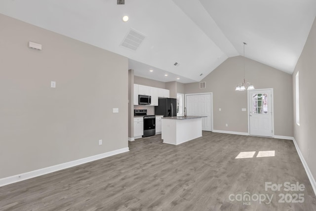 kitchen with light wood finished floors, white cabinets, open floor plan, a center island, and stainless steel appliances