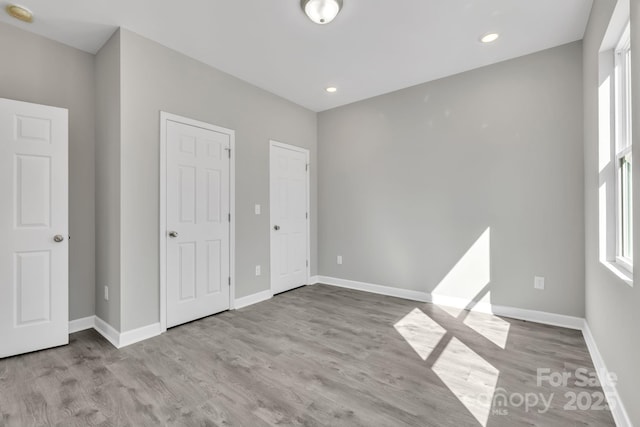 unfurnished bedroom with recessed lighting, wood finished floors, and baseboards