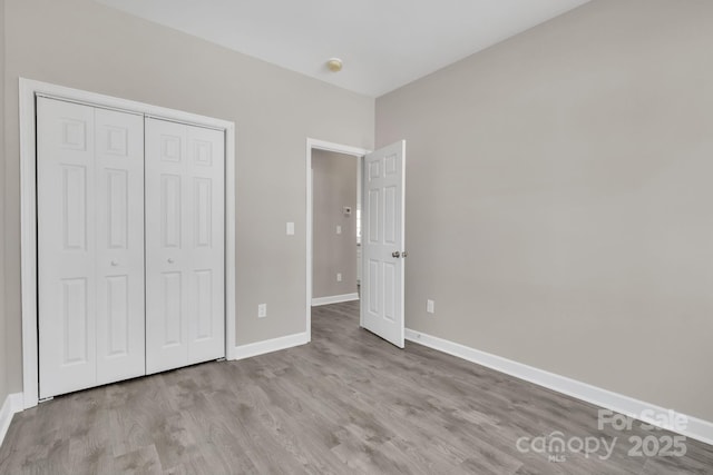 unfurnished bedroom with a closet, wood finished floors, and baseboards