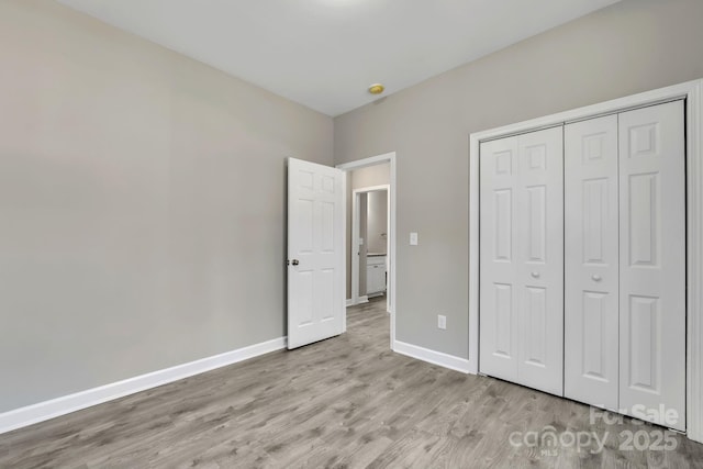 unfurnished bedroom featuring a closet, baseboards, and wood finished floors