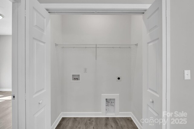 clothes washing area featuring dark wood-style flooring, hookup for a washing machine, electric dryer hookup, laundry area, and baseboards