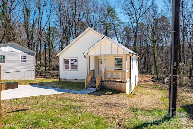 view of front facade with board and batten siding, crawl space, a porch, and a front lawn