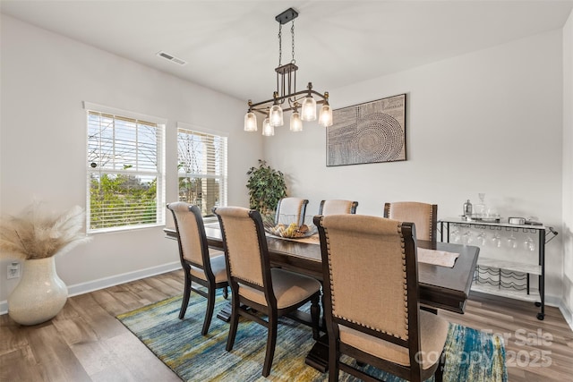 dining area featuring visible vents, baseboards, and wood finished floors