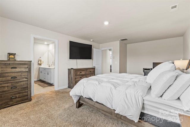 bedroom featuring connected bathroom, baseboards, visible vents, and light carpet