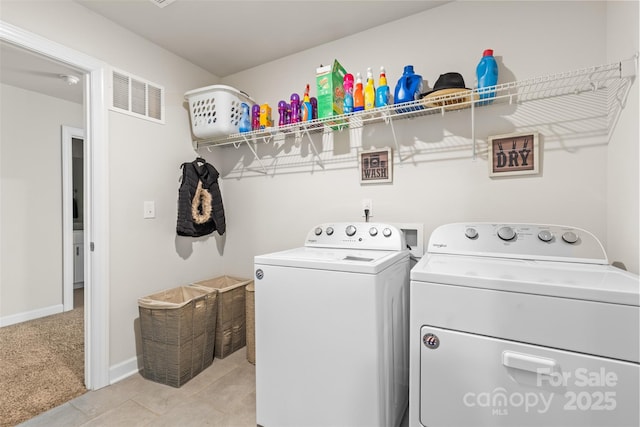 clothes washing area with visible vents, light carpet, washer and clothes dryer, baseboards, and laundry area