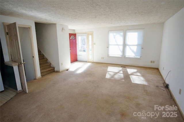 unfurnished room with carpet, stairs, baseboards, and a textured ceiling