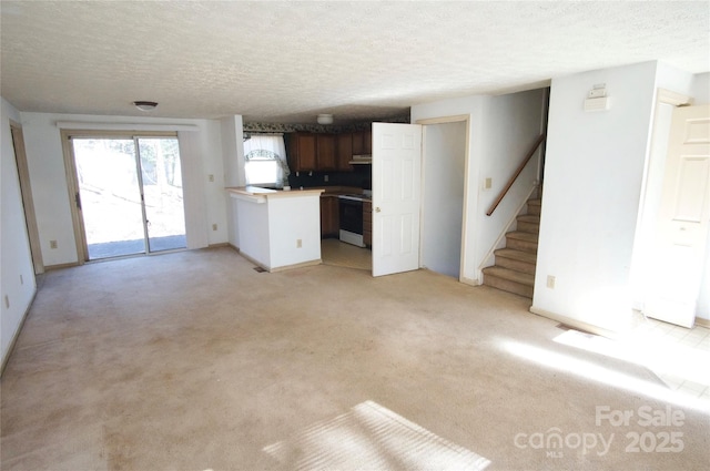 unfurnished living room with light colored carpet, a textured ceiling, and stairs