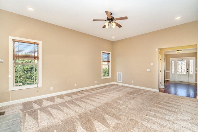 carpeted spare room featuring plenty of natural light, visible vents, baseboards, and recessed lighting