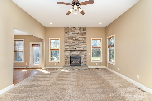 unfurnished living room featuring carpet floors, recessed lighting, a stone fireplace, and baseboards