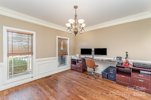 office space featuring visible vents, a wainscoted wall, ornamental molding, light wood-style floors, and a notable chandelier