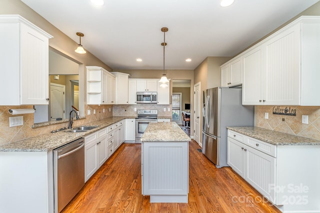 kitchen with light wood finished floors, appliances with stainless steel finishes, a sink, and a center island