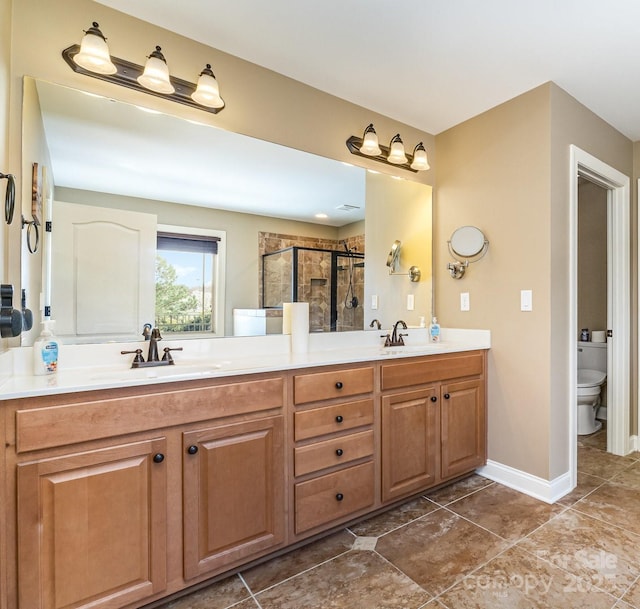 bathroom featuring a sink, double vanity, a shower stall, and toilet