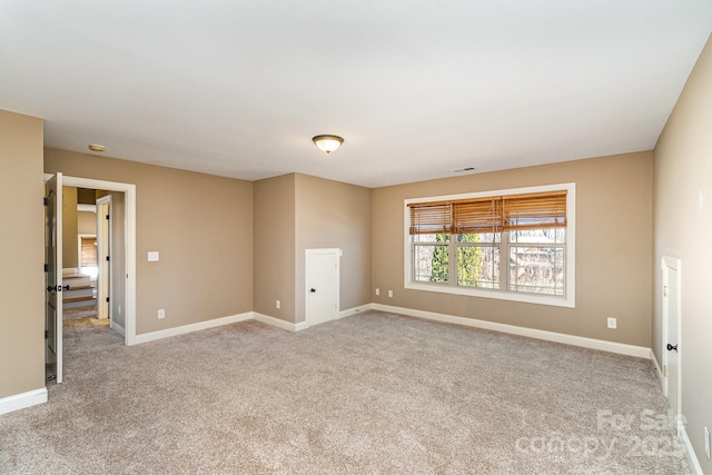 carpeted spare room with visible vents and baseboards