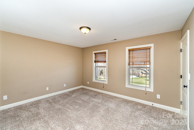 unfurnished room with carpet, visible vents, and baseboards