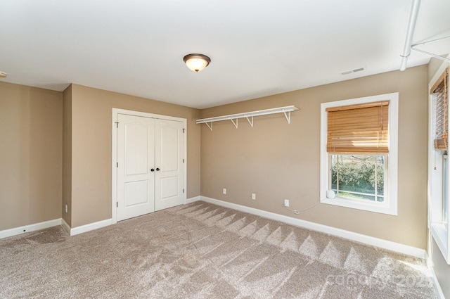 unfurnished bedroom with a closet, carpet flooring, visible vents, and baseboards