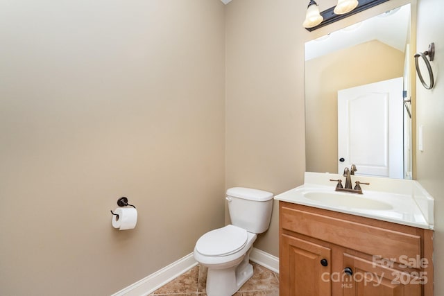 half bathroom featuring toilet, tile patterned flooring, baseboards, and vanity