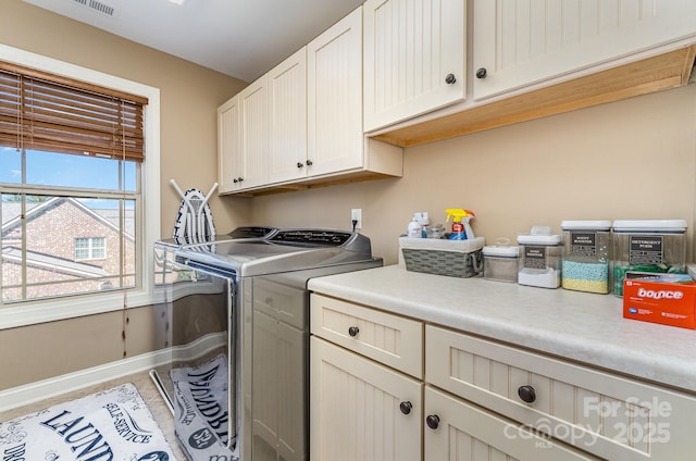 washroom with cabinet space, baseboards, and separate washer and dryer