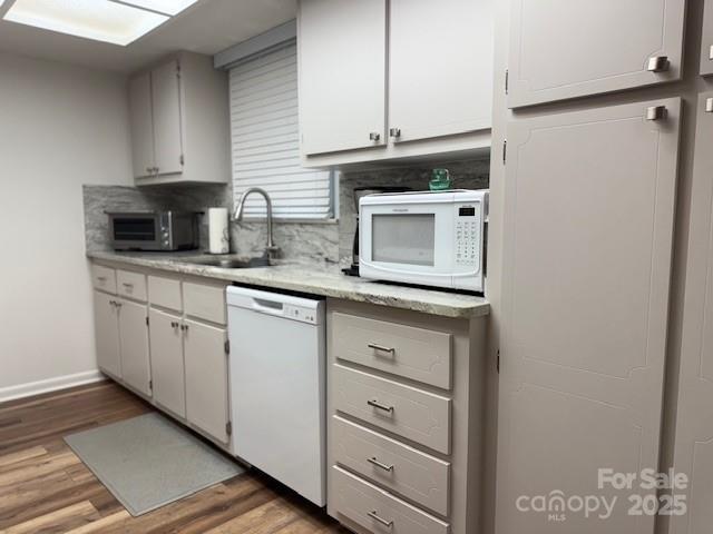 kitchen featuring light wood-type flooring, white appliances, light countertops, and a sink