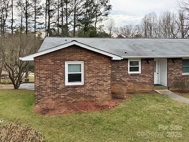 view of side of property featuring brick siding and a yard