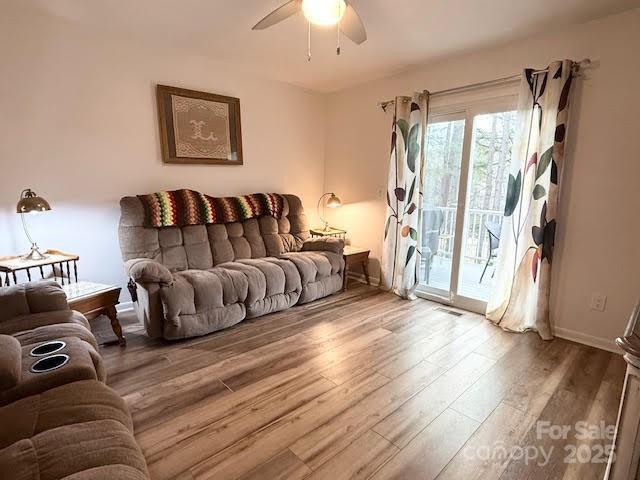 living room with ceiling fan, visible vents, baseboards, and wood finished floors